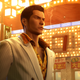 A mobster wearing a wide lapel suit smokes a cigarette in Tokyo in Yakuza 0.